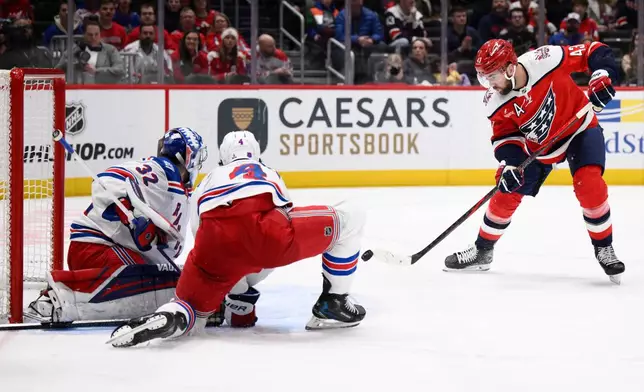 Washington Capitals right wing Tom Wilson (43) shoots the puck for a goal against New York Rangers goaltender Jonathan Quick (32) and defenseman Braden Schneider (4) during the second period of an NHL hockey game, Wednesday, Dec. 31, 2025, in Washington. (AP Photo/Nick Wass)