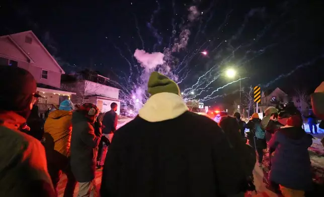 People react after a firework was set off near the scene of a reported shooting Wednesday, Jan. 14, 2026, in Minneapolis. (AP Photo/Abbie Parr)