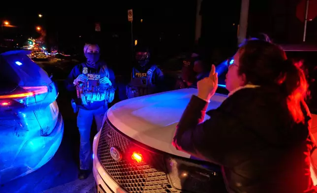 A woman confronts a federal immigration officer at the scene of a reported shooting Wednesday, Jan. 14, 2026, in Minneapolis. (AP Photo/John Locher)