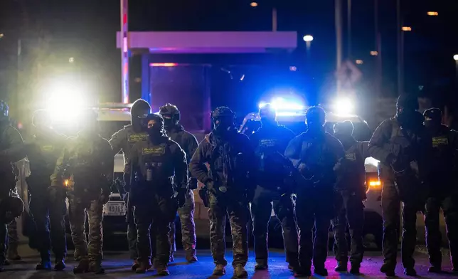 Federal officers stand guard after detaining people outside of Bishop Henry Whipple Federal Building, Tuesday, Jan. 13, 2026, in Minneapolis. (AP Photo/Adam Gray)