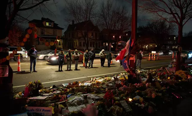 People visits a makeshift memorial for Renee Good, who was fatally shot by an ICE officer last week, Tuesday, Jan. 13, 2026, in Minneapolis. (AP Photo/John Locher)
