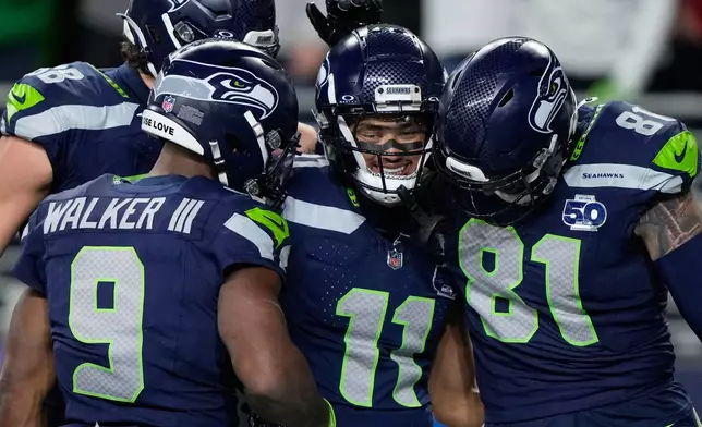 Seattle Seahawks wide receiver Jaxon Smith-Njigba (11) celebrates with teammates after scoring a touchdown during the first half of an NFL football divisional playoff game against the San Francisco 49ers, Saturday, Jan. 17, 2026, in Seattle. (AP Photo/Stephen Brashear)