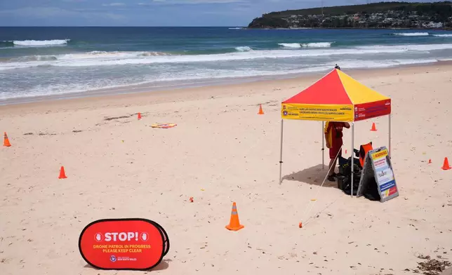 A man is stationed at North Steyne Beach in Sydney as he uses a drone to scan the water, Tuesday, Jan. 20, 2026, after a series of shark attacks. (AP Photo/Rick Rycroft)