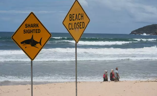 People walk on the sand at North Steyne Beach in Sydney, Tuesday, Jan. 20, 2026, after a series of shark attacks. (AP Photo/Rick Rycroft)