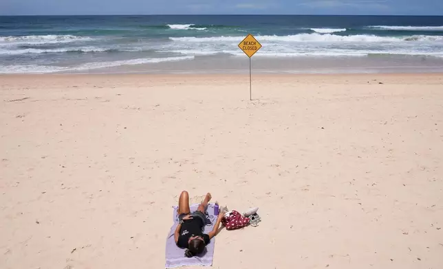 A lone sun bather relaxes at North Steyne Beach in Sydney, Tuesday, Jan. 20, 2026, after a series of shark attacks. (AP Photo/Rick Rycroft)