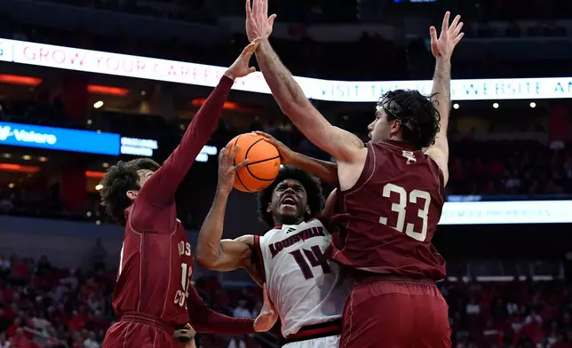 Louisville guard Adrian Wooley (14) attempts a shot through Boston College guard Luka Toews (10), left, and center Boden Kapke (33) during the second half of an NCAA college basketball game in Louisville, Ky., Saturday, Jan. 10, 2026. (AP Photo/Timothy D. Easley)