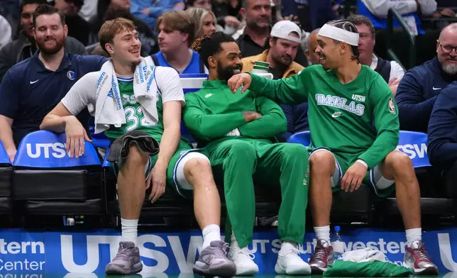 Dallas Mavericks forward Cooper Flagg, left, guard D'Angelo Russell, center, and guard Ryan Nembhard react on the bench during the first half of an NBA basketball game against the Brooklyn Nets Monday, Jan. 12, 2026, in Dallas. (AP Photo/Julio Cortez)