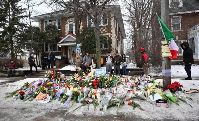 People gather around a makeshift memorial honoring Renee Good who was fatally shot by a federal law enforcement agent near the site of the shooting in Minneapolis, Thursday, Jan. 8, 2026. (AP Photo/Tom Baker)