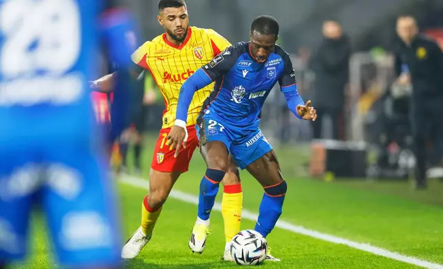 Auxerre's Lamine Sy, right, challenges for the ball with Lens' Matthieu Udol during the French League One soccer match between Lens and Auxerre in Lens, France, Saturday, Jan. 17, 2026. (AP Photo/Jean-Francois Badias)