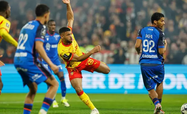 Lens' Matthieu Udol, centre, and Auxerre's Clement Akpa, right, in action during the French League One soccer match between Lens and Auxerre in Lens, France, Saturday, Jan. 17, 2026. (AP Photo/Jean-Francois Badias)