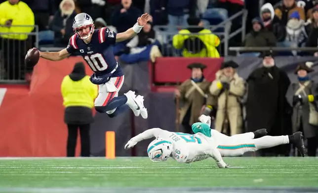 New England Patriots quarterback Drake Maye, left, escapes pressure from Miami Dolphins linebacker Quinton Bell during the first half of an NFL football game in Foxborough, Mass., Sunday, Jan. 4, 2026. (AP Photo/Charles Krupa)