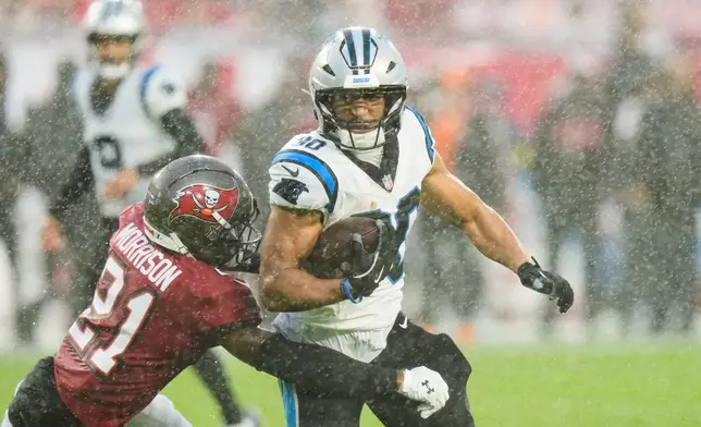 Carolina Panthers running back Chuba Hubbard (30) runs around the tackle attempt from Tampa Bay Buccaneers cornerback Benjamin Morrison (21) during the first half of an NFL football game Saturday, Jan. 3, 2026, in Tampa, Fla. (AP Photo/Chris O'Meara)