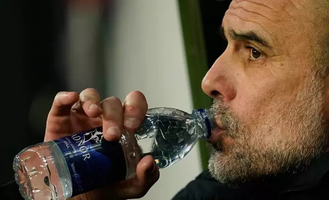 Manchester City's head coach Pep Guardiola drinks water as he attends the start of the English League Cup semifinal first leg soccer match between Newcastle and Manchester City in Newcastle, England, Tuesday, Jan. 13, 2026. (AP Photo/Dave Thompson)