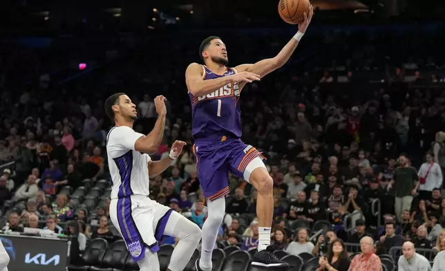 Phoenix Suns guard Devin Booker (1) drives past Sacramento Kings forward Keegan Murray, left, during the second half of an NBA basketball game, Friday, Jan. 2, 2026, in Phoenix. (AP Photo/Rick Scuteri)