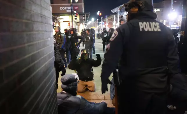 A protester raises their arms on the ground as law enforcement make arrests after declaring an unlawful assembly during a noise demonstration outside the Graduate by Hilton Minneapolis hotel on Wednesday, Jan. 28, 2026, in Minneapolis. (AP Photo/Adam Gray)