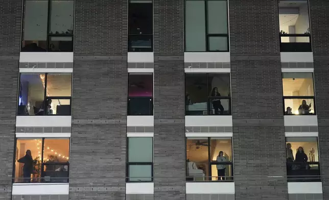 People watch from a building as police prepare to make arrests during a noise demonstration outside the Graduate by Hilton Minneapolis hotel on Wednesday, Jan. 28, 2026, in Minneapolis. (AP Photo/Adam Gray)