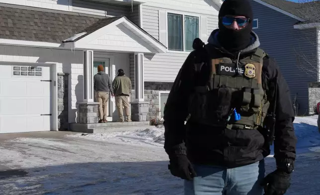 Federal agents knock on a door of a residence on Wednesday, Jan. 28, 2026, in Blaine, Minn. (AP Photo/Adam Gray)