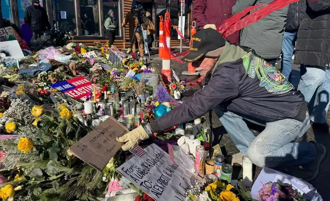 Vietnam war veteran Donnie McMillan places a sign that says "In remembrance of my angel" at a memorial set up at the location where Veterans Affairs nurse Alex Pretti was shot by U.S. federal agents, in Minneapolis, Wednesday, Jan. 28, 2026. (AP Photo/Jack Brook)