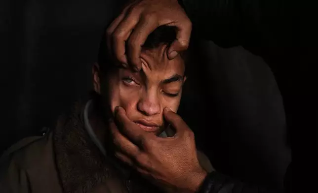 Mahmoud Abu Ishaq, 14, who is suffering vision loss due to a corneal condition, has his eye shown to the camera by his father as they await permission to travel outside the Gaza Strip for medical treatment, in Khan Younis, Gaza Strip, Tuesday, Jan. 27, 2026. (AP Photo/Abdel Kareem Hana)