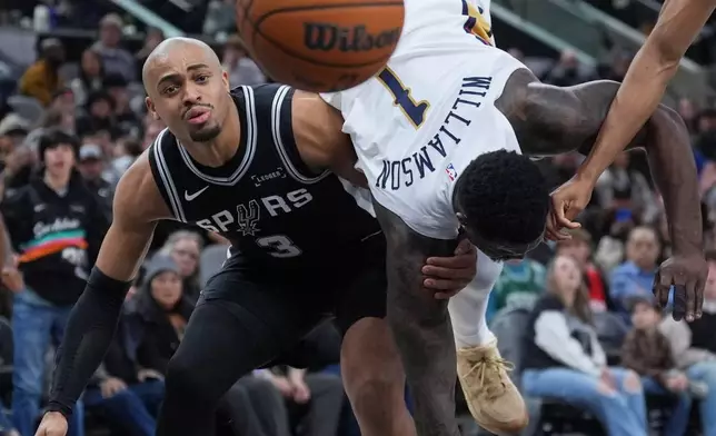 New Orleans Pelicans forward Zion Williamson (1) flips over San Antonio Spurs forward Keldon Johnson (3) as they chase a rebound during the second half of an NBA basketball game in San Antonio, Sunday, Jan. 25, 2026. (AP Photo/Eric Gay)