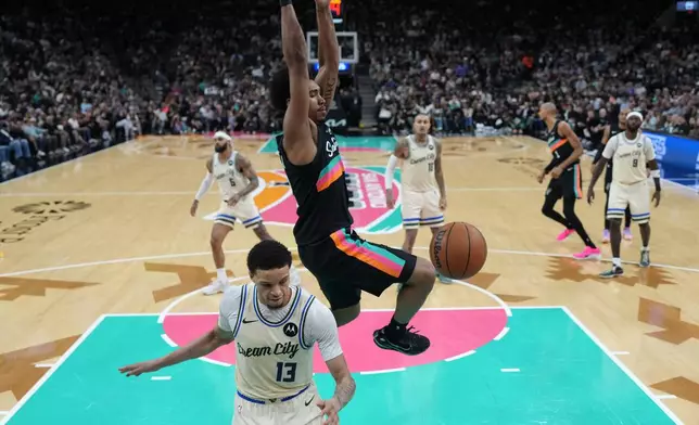 San Antonio Spurs guard Dylan Harper (2) scores over Milwaukee Bucks guard Ryan Rollins (13) during the second half of an NBA basketball game in San Antonio, Thursday, Jan. 15, 2026. (AP Photo/Eric Gay)