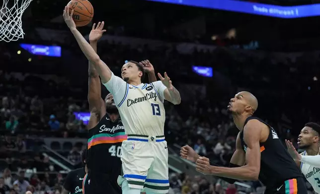 Milwaukee Bucks guard Ryan Rollins (13) scores past San Antonio Spurs forward Harrison Barnes (40) and forward Victor Wembanyama (1) during the second half of an NBA basketball game in San Antonio, Thursday, Jan. 15, 2026. (AP Photo/Eric Gay)