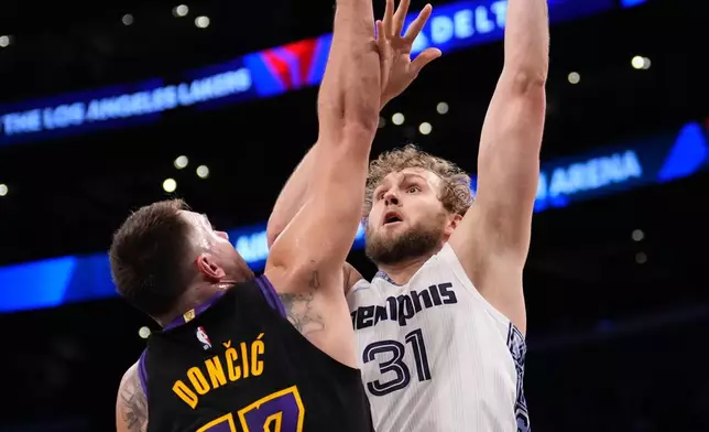 Memphis Grizzlies center Jock Landale, right, shoots as Los Angeles Lakers guard Luka Doncic defends during the first half of an NBA basketball game Friday, Jan. 2, 2026, in Los Angeles. (AP Photo/Mark J. Terrill)