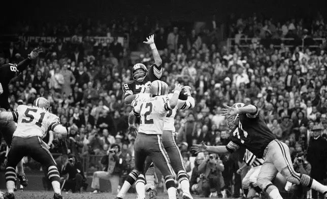 FILE - Dallas Cowboys quarterback Roger Staubach rears back to pass 22 yards to Ron Sellers (88) on a third down play late in the second quarter, Dec. 31, 1972. (AP Photo)