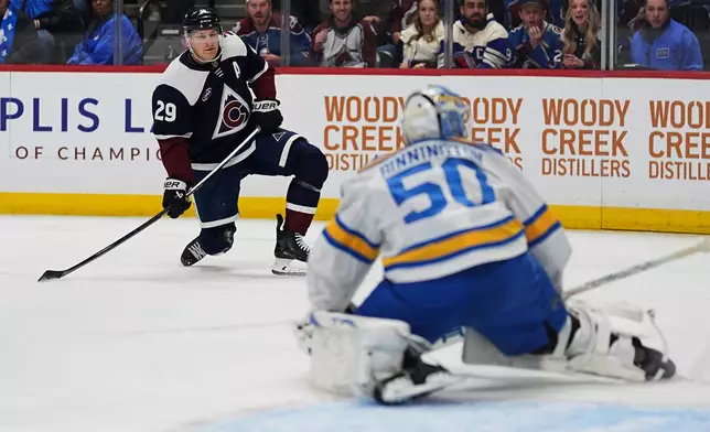 Colorado Avalanche center Nathan MacKinnon, back, shoots the puck at St. Louis Blues goaltender Jordan Binnington in the first period of an NHL hockey game, Wednesday, Dec. 31, 2025, in Denver. (AP Photo/David Zalubowski)