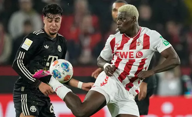 Cologne's Ragnar Ache, right, and Bayern's Aleksandar Pavlovic challenge for the ball during the German Bundesliga soccer match between 1.FC Koeln and FC Bayern Munich in Cologne, Germany, Wednesday, Jan. 14, 2026. (AP Photo/Martin Meissner)
