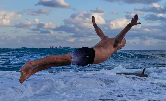 A man jumps into the Mediterranean Sea during an early morning swim as temperatures hovered around 10 degrees Celsius, 50 degrees Fahrenheit, in Beirut, Lebanon, Wednesday, Jan. 14, 2026. (AP Photo/Hassan Ammar)