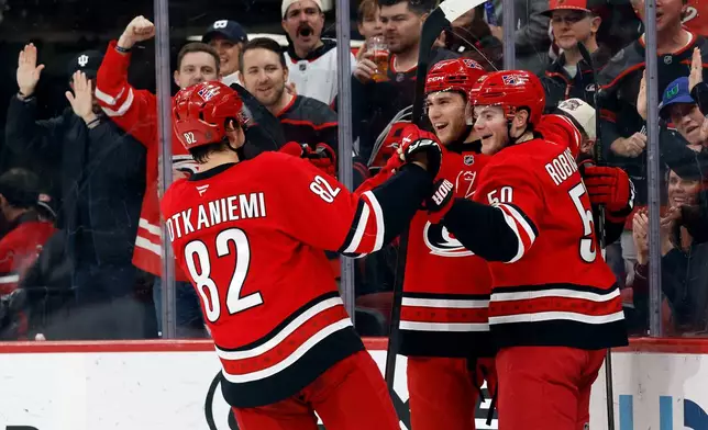 Carolina Hurricanes' Mark Jankowski, center, celebrates his goal with Carolina Hurricanes' Eric Robinson, right, and Jesperi Kotkaniemi (82) during the second period of an NHL hockey game against the Florida Panthers in Raleigh, N.C., Friday, Jan. 16, 2026. (AP Photo/Karl DeBlaker)