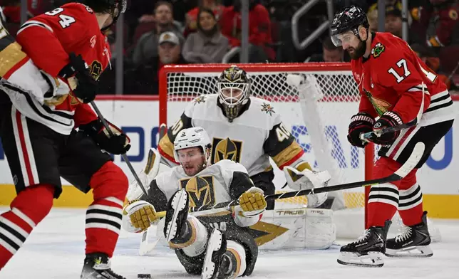Vegas Golden Knights' Jeremy Lauzon (5) battles Chicago Blackhawks' Colton Dach (34) for the puck during the second period of an NHL hockey game Sunday, Jan. 4, 2026, in Chicago. (AP Photo/Paul Beaty)