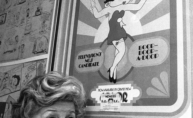 FILE - Mae Questel, who provided the loopy, child-like voice of cartoon characters Betty Boop and Olive Oyl, poses in this 1978 file photo with a poster of Betty Boop. . (AP Photo/File)