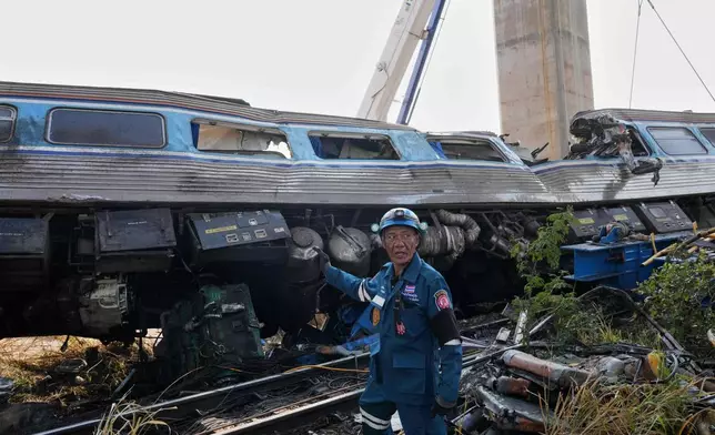 A rescuer stands near the wreckage after a construction crane fell into a passenger train in Nakhon Ratchasima province, Thailand, Wednesday, Jan.14, 2026. (AP Photo/Sakchai Lalit))