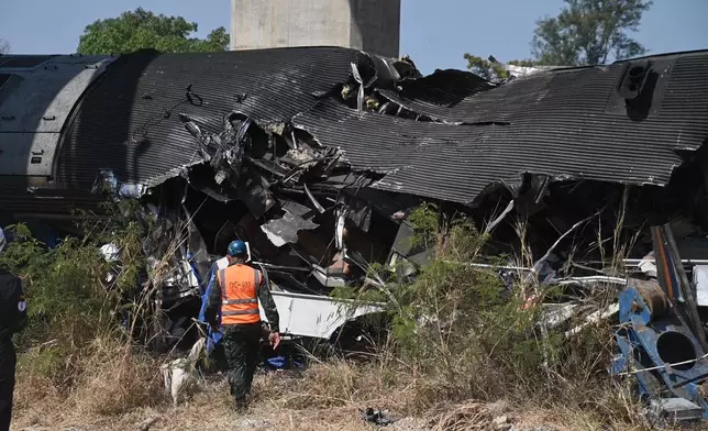 An aid workers at the scene after a construction crane fell into a passenger train in Nakhon Ratchasima province, Thailand, Wednesday, Jan. 14, 2026. (AP Photo/Nathathida Adireksarn)