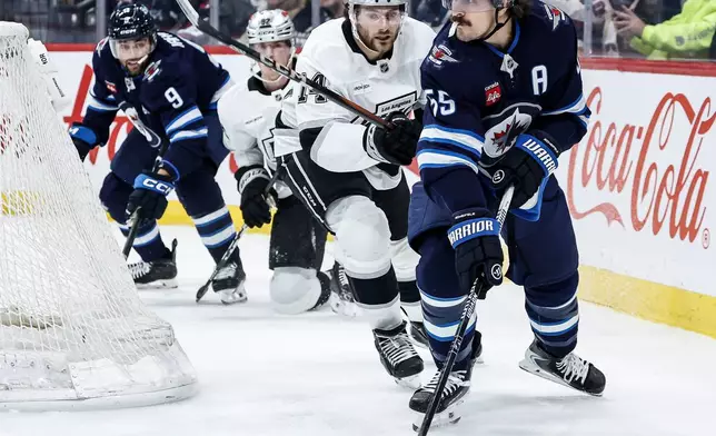 Winnipeg Jets' Mark Scheifele (55) looks to pass the puck with Los Angeles Kings' Alex Laferriere (14) in pursuit during second-period NHL hockey game action in Winnipeg, Manitoba, Friday, Jan. 9, 2026. (John Woods/The Canadian Press via AP)
