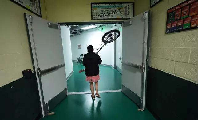 Red Panda carries her unicycle back to her dressing room after performing at halftime of an NCAA college basketball game between Miami and Stanford in Coral Gables, Fla., Wednesday, Jan. 28, 2026. (AP Photo/Rebecca Blackwell)