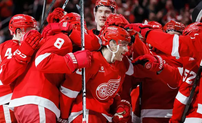 Detroit Red Wings right wing Patrick Kane, center, is surround by teammates after recording his 1,375th point to pass Mike Modano and break the NHL record for points by a player born in the United States, during the second period of an NHL hockey game Thursday, Jan. 29, 2026, in Detroit. (AP Photo/Duane Burleson)