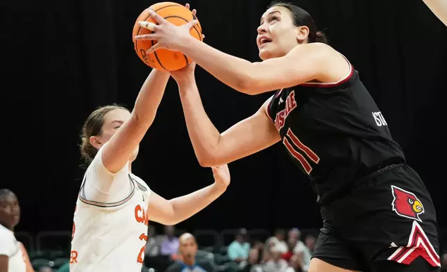 Louisville forward Elif Istanbulluoglu (11) goes to the basket as Miami guard Simone Pelish, left, defends during the first half of an NCAA college basketball game, Thursday, Jan. 8, 2026, in Coral Gables, Fla. (AP Photo/Lynne Sladky)
