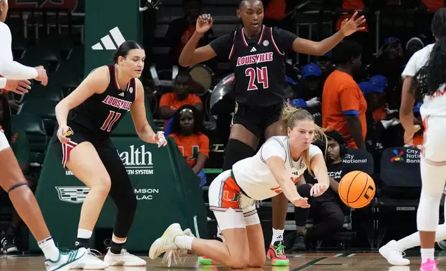 Miami forward Natalie Wetzel loses control of the ball as Louisville forward Elif Istanbulluoglu (11) and forward Grace Mbugua (24) defend during the first half of an NCAA college basketball game, Thursday, Jan. 8, 2026, in Coral Gables, Fla. (AP Photo/Lynne Sladky)