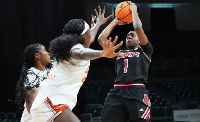 Louisville guard Reyna Scott (1) shoots as Miami center Candace Kpetikou, center, defends during the first half of an NCAA college basketball game, Thursday, Jan. 8, 2026, in Coral Gables, Fla. (AP Photo/Lynne Sladky)