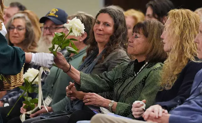 Roses are given to survivors on the one-year anniversary of the Palisades Fire in the Pacific Palisades neighborhood of Los Angeles Wednesday, Jan. 7, 2026. (AP Photo/Jae C. Hong)