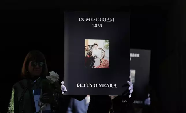 Photos of victims are carried on the one-year anniversary of the Palisades Fire in the Pacific Palisades neighborhood of Los Angeles Wednesday, Jan. 7, 2026. (AP Photo/Jae C. Hong)