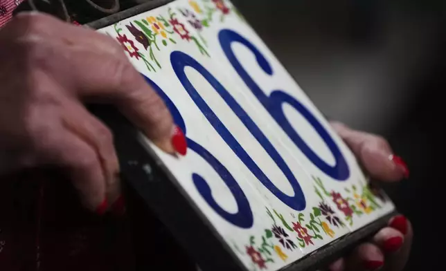Jill Genzon holds a placard with her home address, which she lost in the Eaton Fire, on the one-year anniversary of the fire Wednesday, Jan. 7, 2026, in Altadena, Calif. (AP Photo/Gregory Bull)