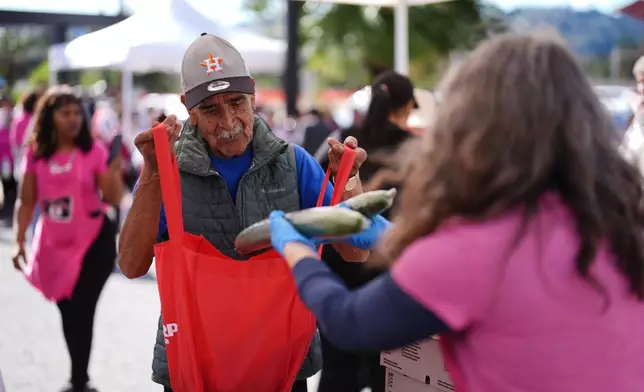 Angel Avila receives food aid at a distribution site for people affected by the wildfires on the one-year anniversary of the Eaton Fire Wednesday, Jan. 7, 2026, in Altadena, Calif. (AP Photo/Gregory Bull)