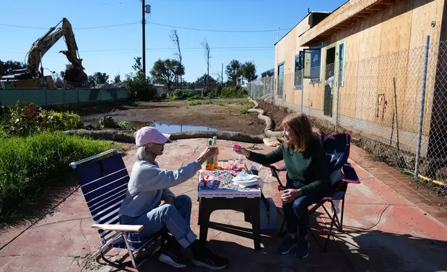 Gail Kass, right, shares a lunch with her neighbor Sandy Oshinomi as homes are rebuilt around them on the one-year anniversary of the Palisades Fire in the Pacific Palisades neighborhood of Los Angeles Wednesday, Jan. 7, 2026. (AP Photo/Jae C. Hong)