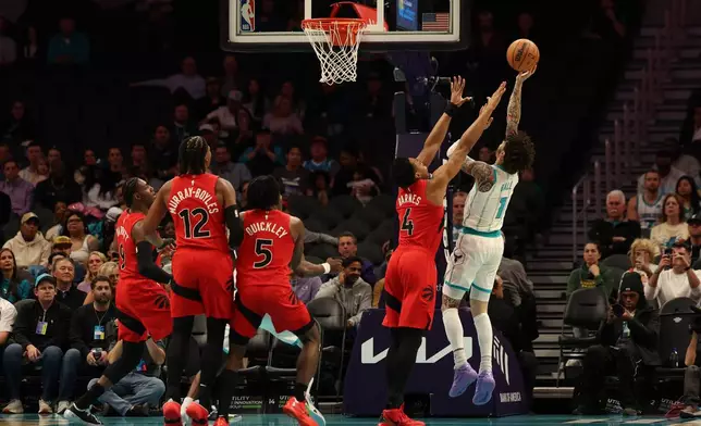 Charlotte Hornets guard Lamelo Ball (1) lays up the ball against Toronto Raptors forward/guard Scottie Barnes (4) during the first half of an NBA basketball game against the Charlotte Hornets, Wednesday, Jan. 7, 2026, in Charlotte, N.C. (AP Photo/Krista Jasso)