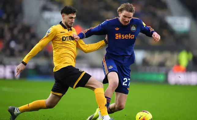 Wolverhampton Wanderers' Santiago Bueno, left, and Newcastle United's Nick Woltemade battle for the ball during the English Premier League soccer match between Wolves and Newcastle United in Wolverhampton, England, Sunday Jan. 18, 2026. (Mike Egerton/PA via AP)