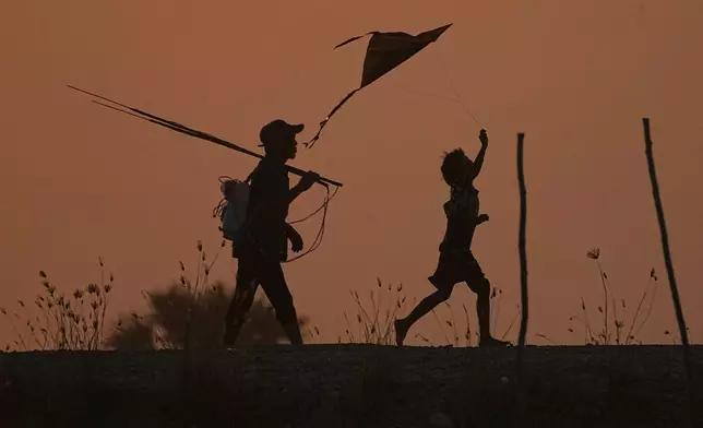 A local boy, right, flies a kite as his father walks home after fishing on the outskirts of Phnom Penh Cambodia, Thursday, Jan 15, 2026.(AP Photo/Heng Sinith)